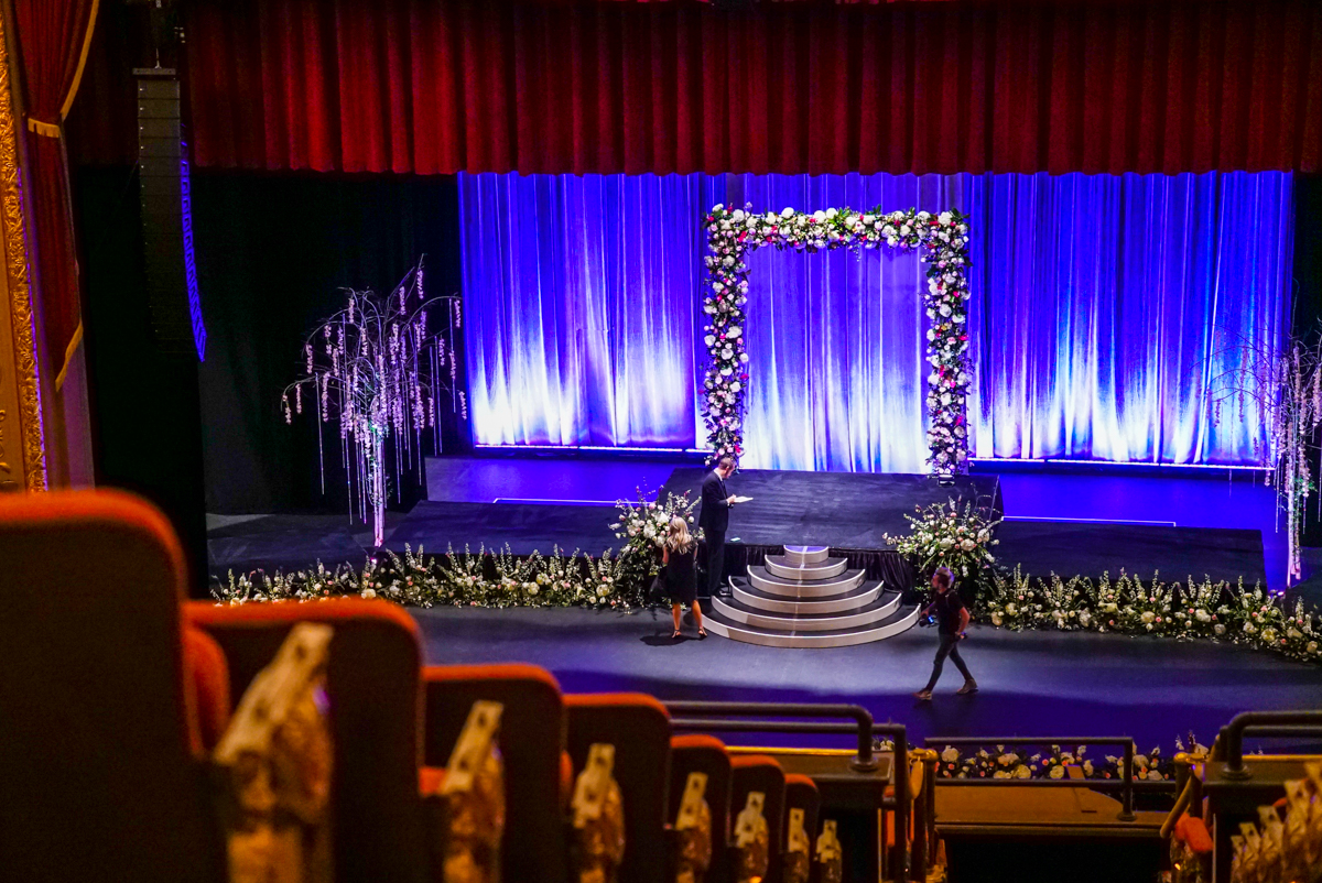 View of flowers and wedding arch on stage from Mezzanine. 