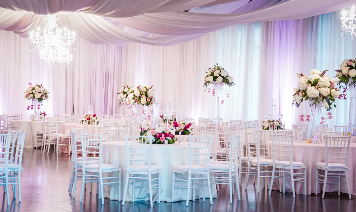 Reception Hall set up for wedding reception, all white with pops of pink.